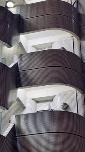 A tiled parking garage stairwell photographed from below, showing curved concrete floor edges wrapped in small square tiles.