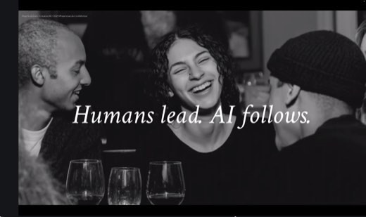 A slide reading "Humans lead. AI follows." over a black-and-white photo of three friends laughing together at a table with wine glasses.